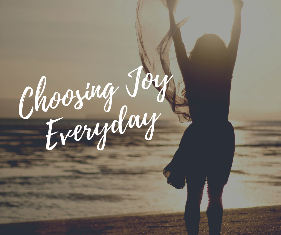 10 Bible verses to help us remember to choose joy everday with a woman on a beach praising the lord and her hands lifted in the air